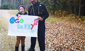 Mike Dube and his son Lincoln standing at the finish line of his run, holding the poster that his son made, saying, “Go Dabby. So proud of you!” - Photo courtesy Mike Dubé