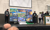 From left: Andrew Mckenzie and Jacob Linklater unveil three paintings created for Sioux North High School, while Joshua Slobozian and Anthony Slobozian, stand alongside their grandfather Don Ningewance, the artist who created the paintings. - Tim Brody / 